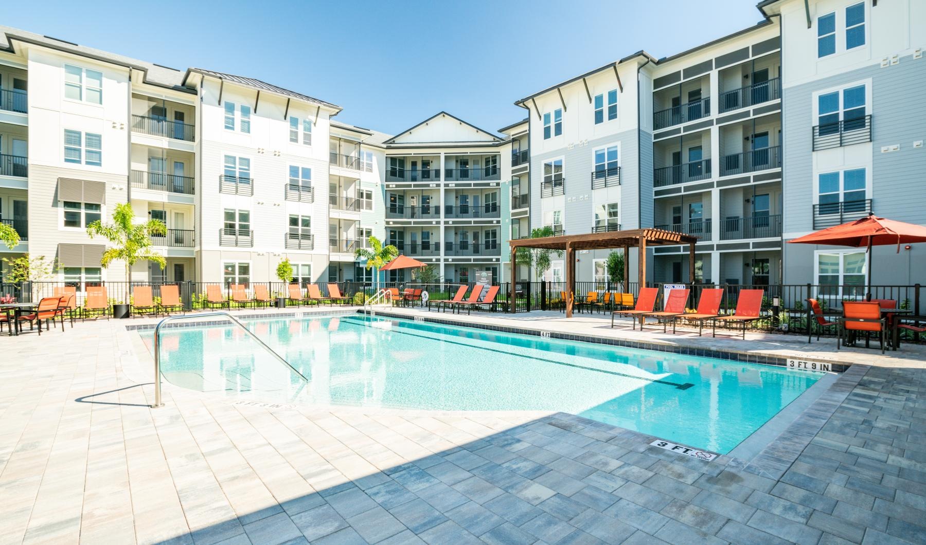 Find your perfect fit at The Pointe at Siena Ridge Outdoor swimming pool at The Pointe at Siena Ridge in Davenport, FL, featuring lounge chairs and umbrellas.